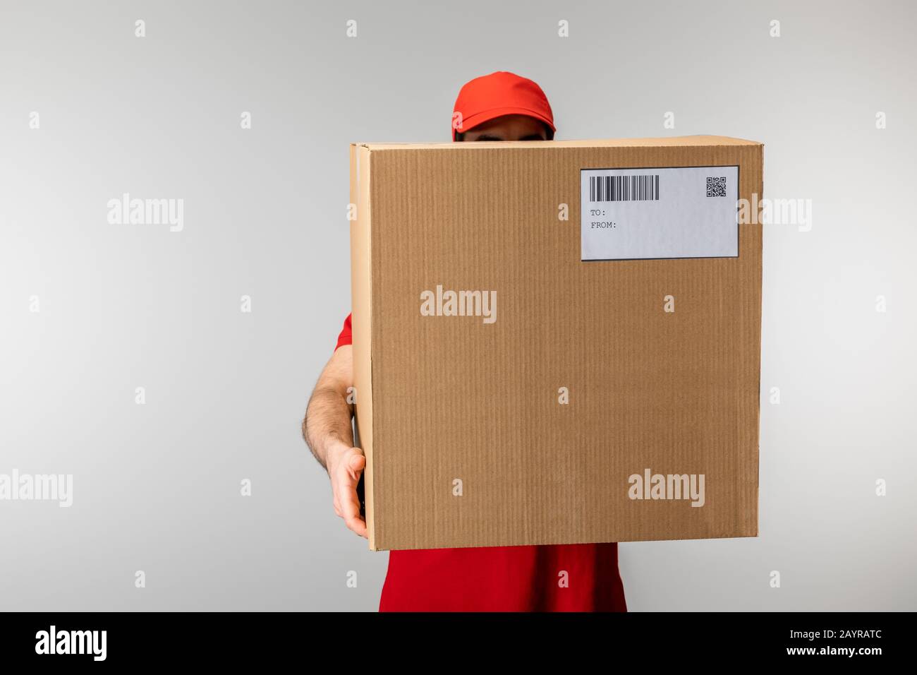 Courier in cap holding box with barcode and qr code on card isolated on