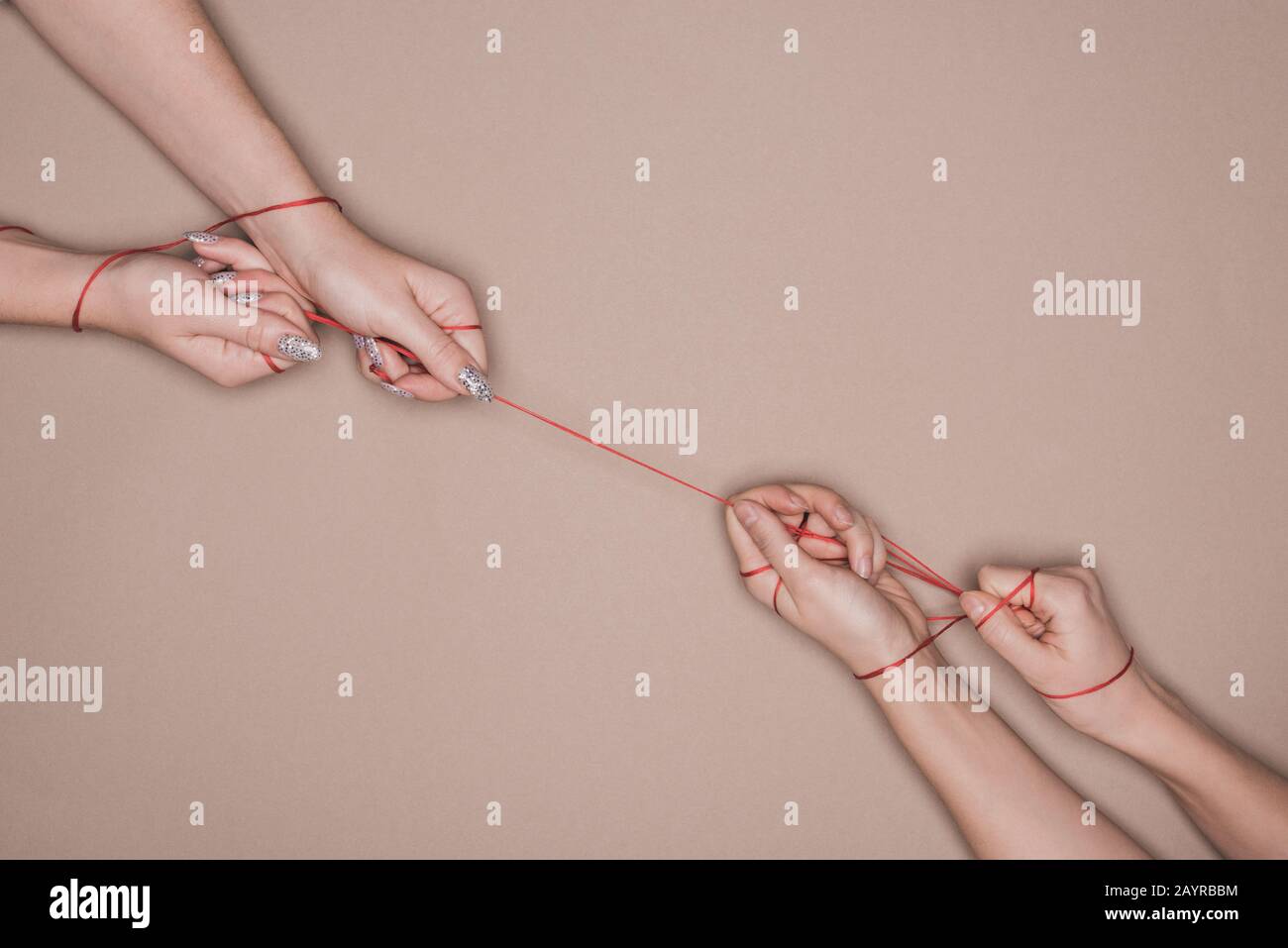 Top view of women pulling red string on beige background Stock Photo ...