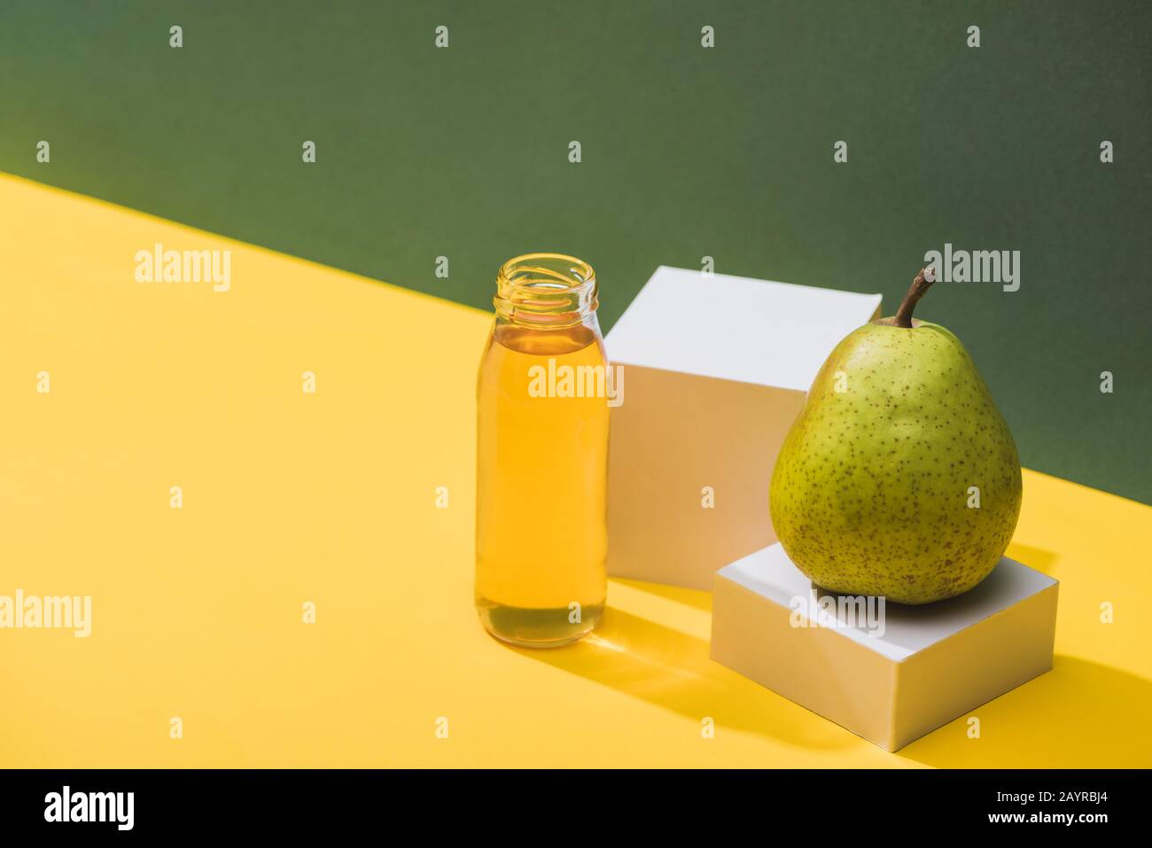 fresh juice in bottle near pear and white cubes on green and yellow