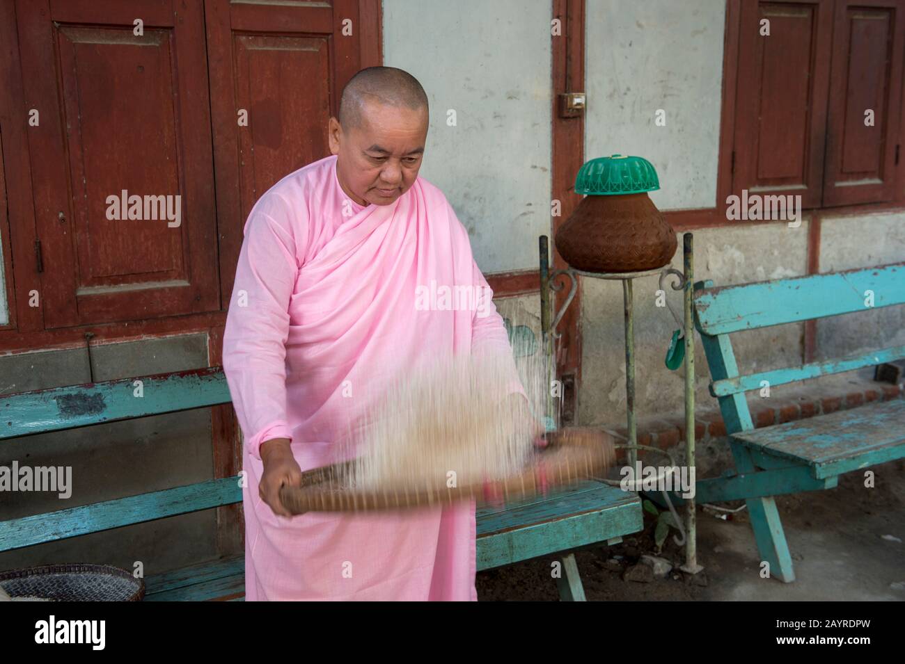 A nun is sifting rice at Zayertheingi, a Buddhist nunnery in Sagaing, a town outside of Mandalay, Myanmar. Stock Photo