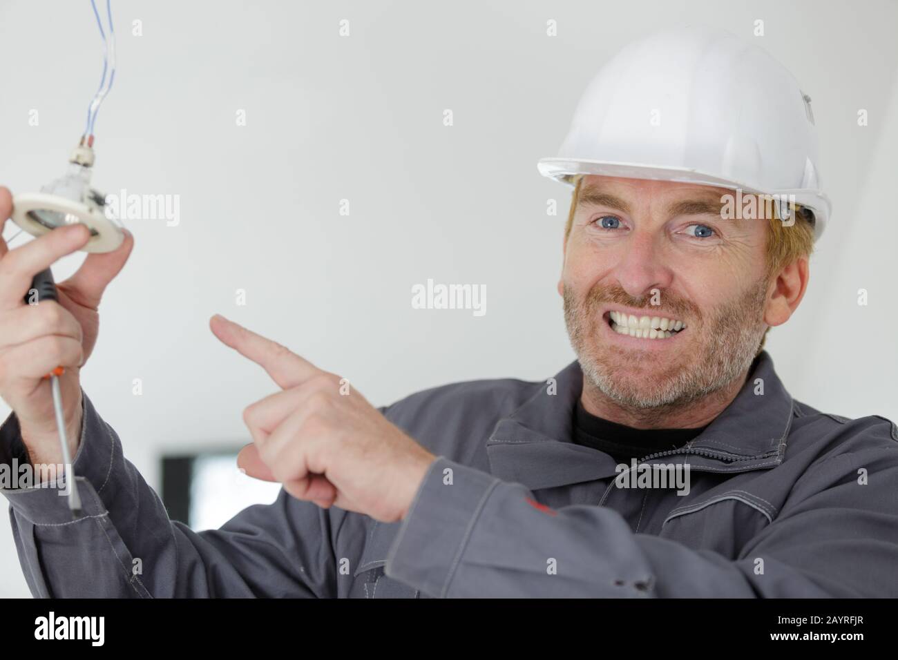 electrician pointing at spot light Stock Photo - Alamy