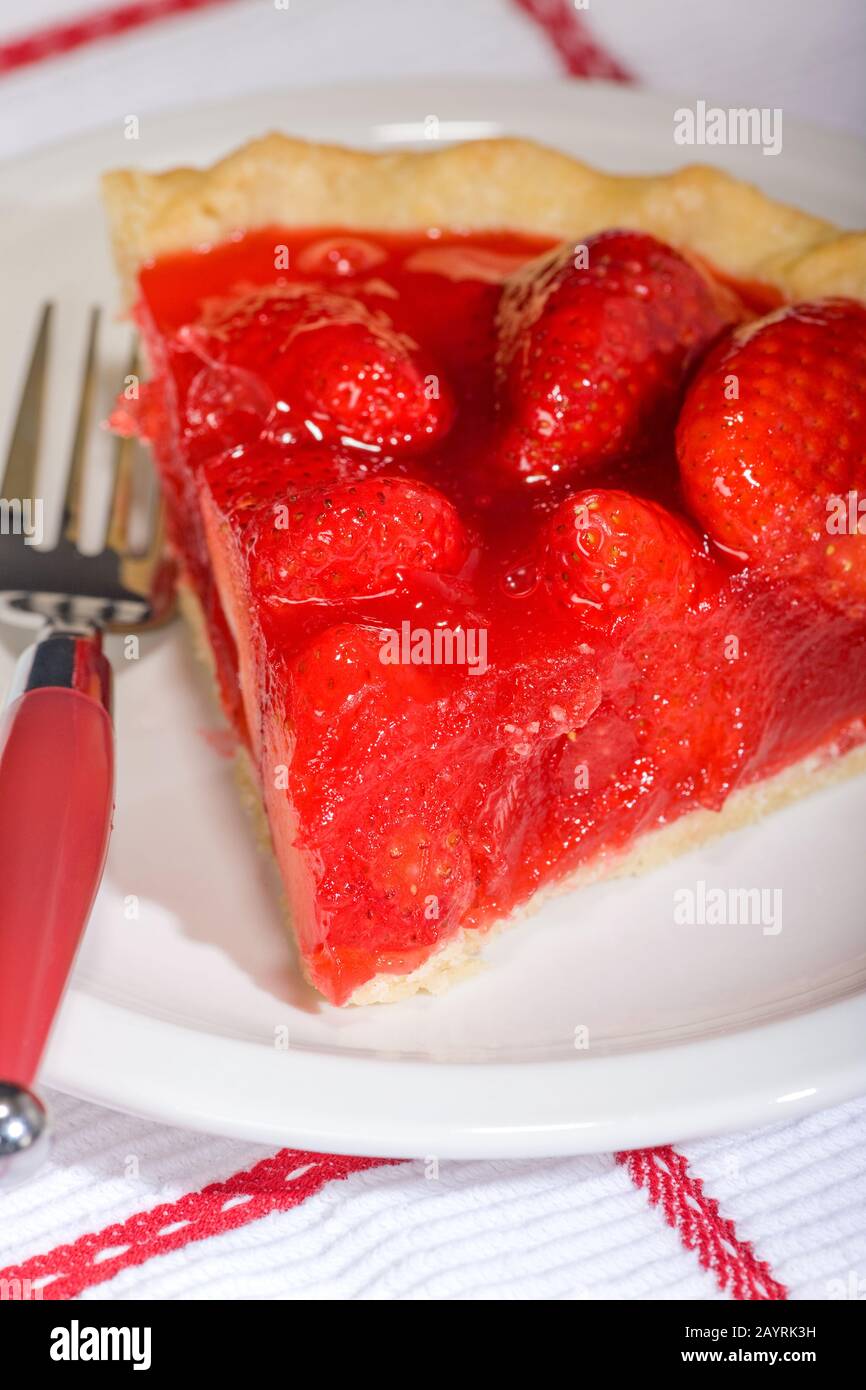 Slice of strawberry pie on a white ceramic plate with red-handled fork Stock Photo