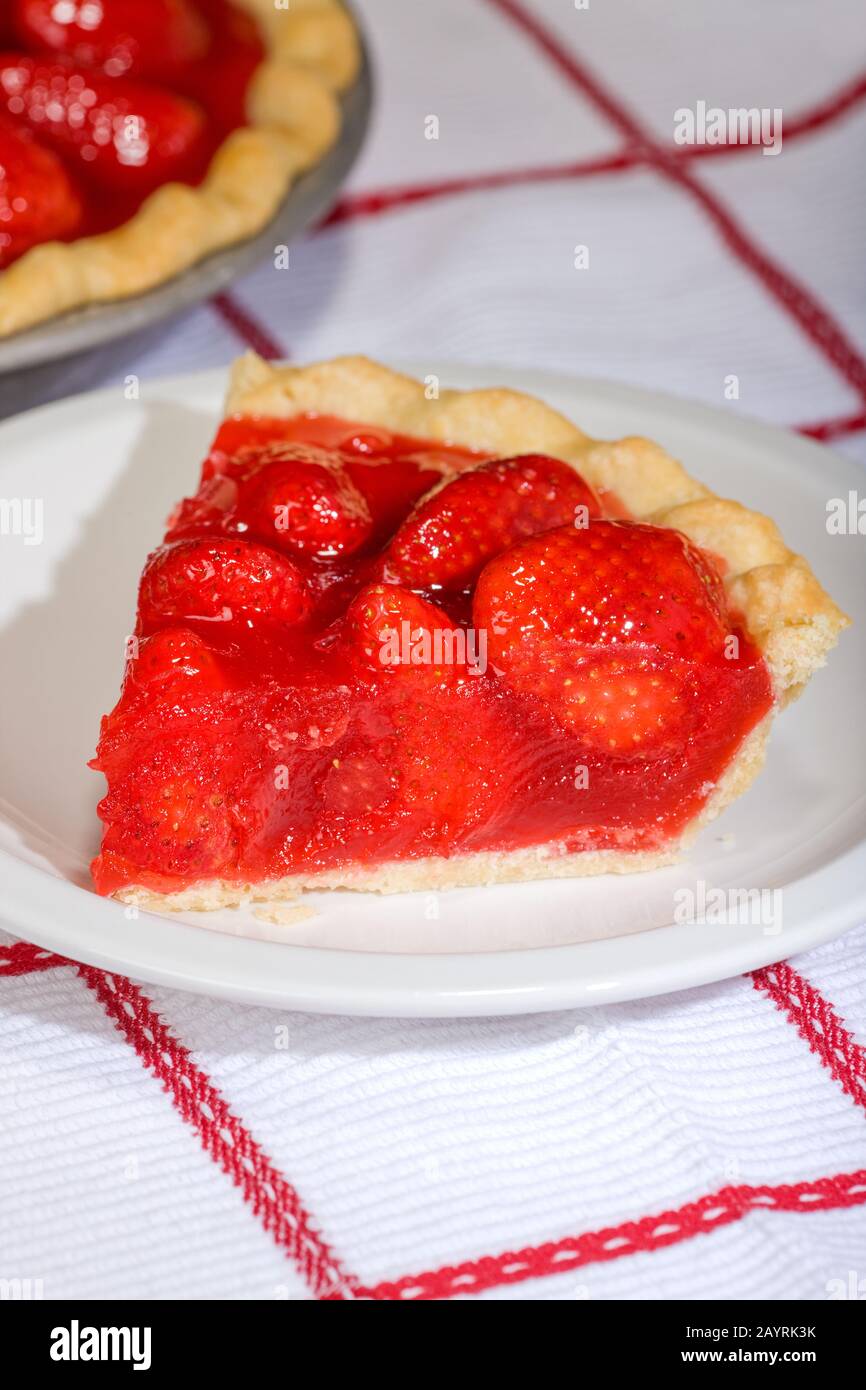Strawberry pie with wedge cut out, with slice of pie on white ceramic plate Stock Photo