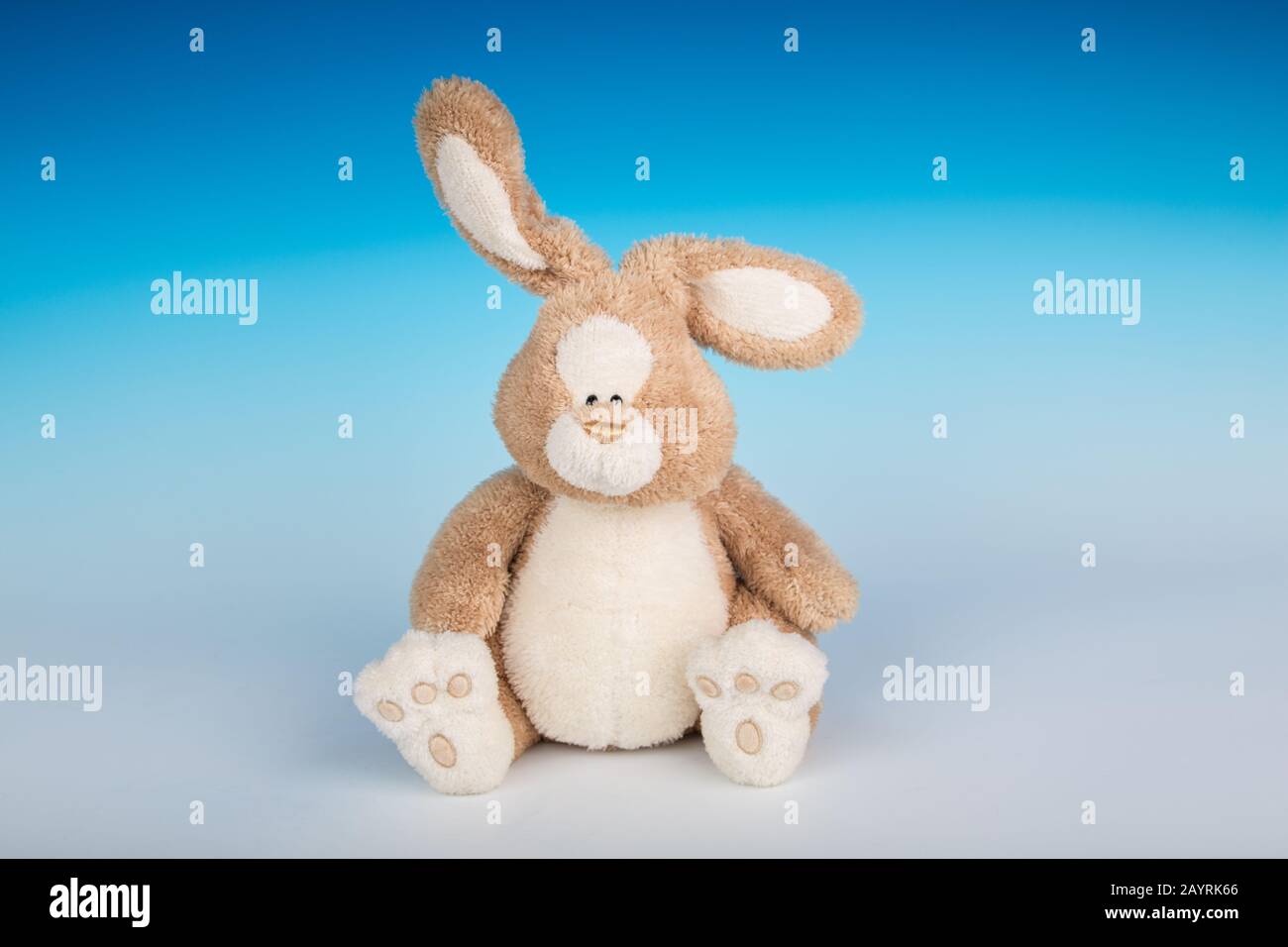 Stuffed toy bunny sitting on a gradient seamless background Stock Photo