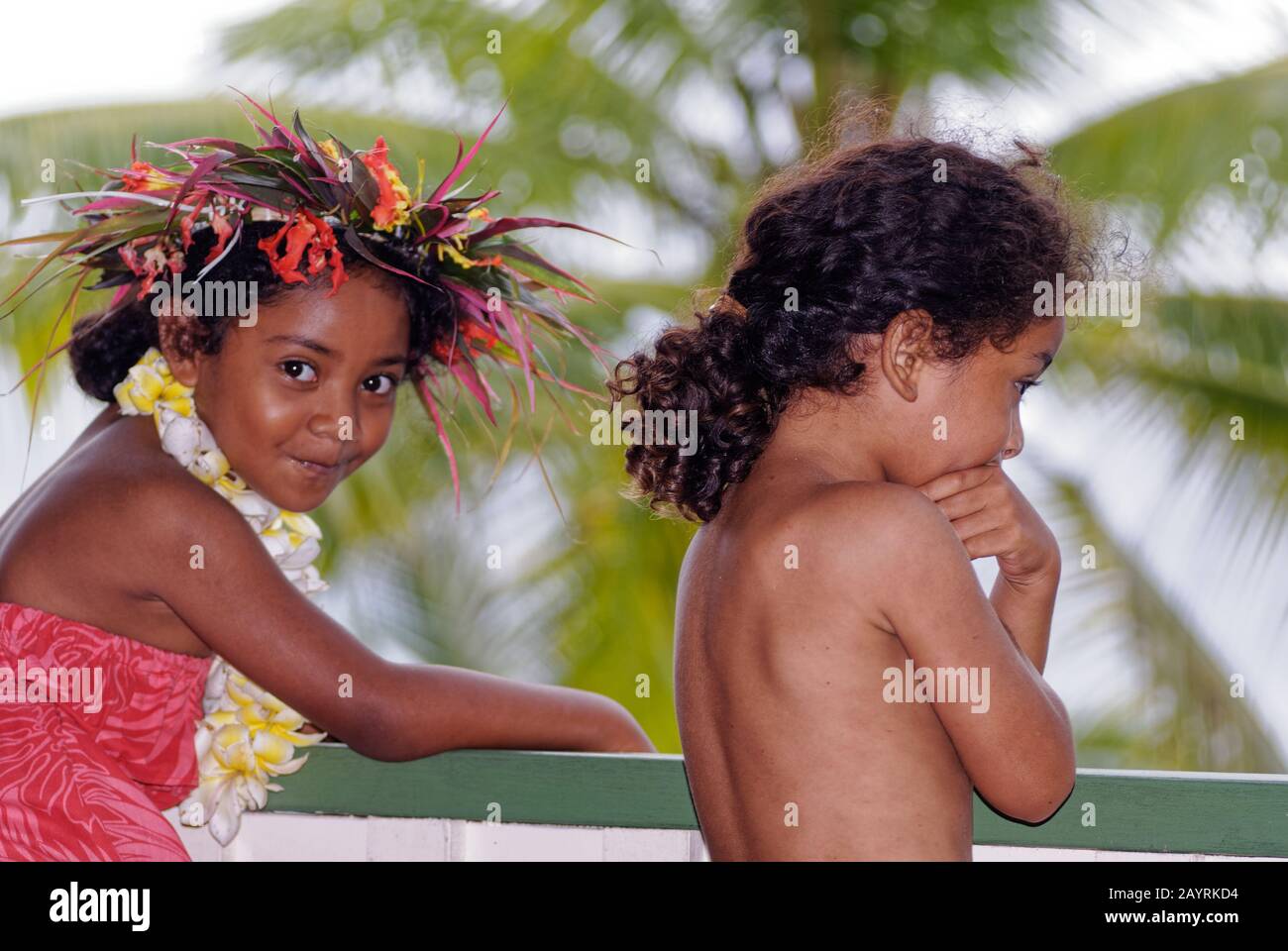 Two Niuean children are standing outside, one is smiling cheekily at the photographer Stock Photo