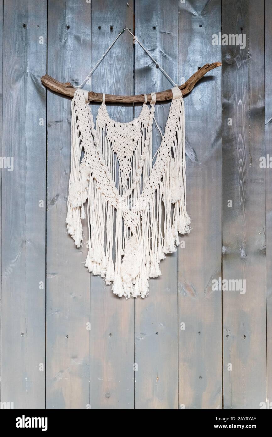 Handmade stylish cotton macrame decoration hanging on a white empty wall. Copy space. Stock Photo