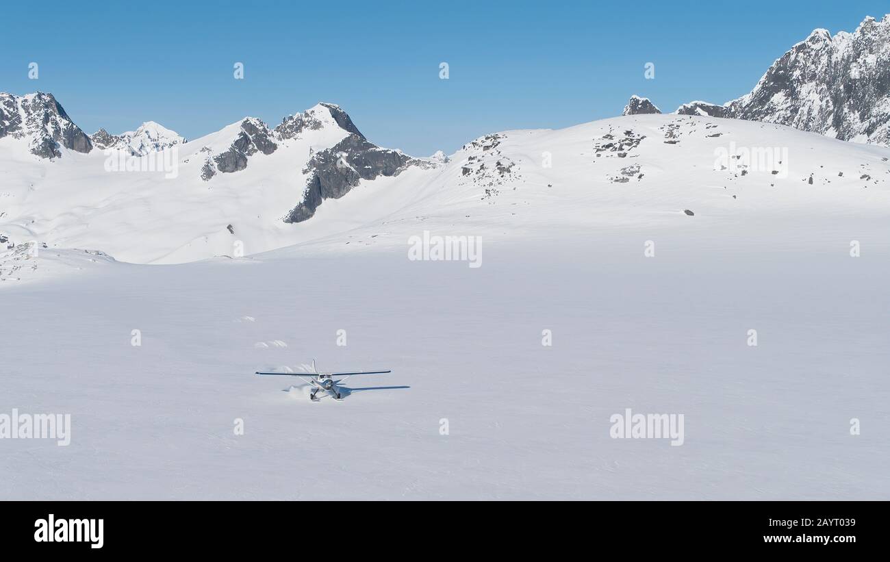 Small plane landing on a snow field in wilderness mountains of Southeast Alaska Stock Photo