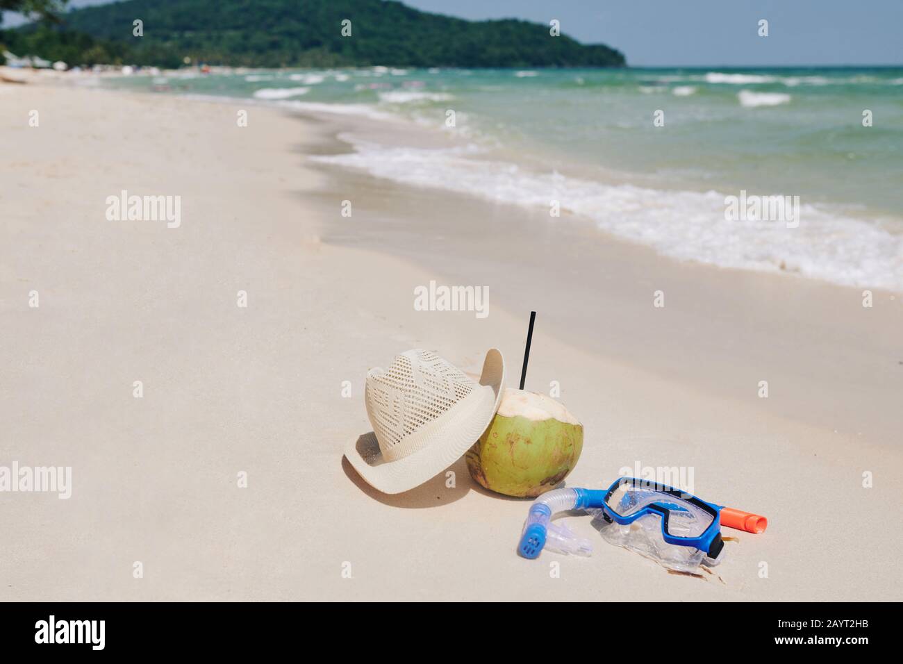 Snorkeling mask, straw hat and coconut cocktail on sandy beach, summer activities concept Stock Photo
