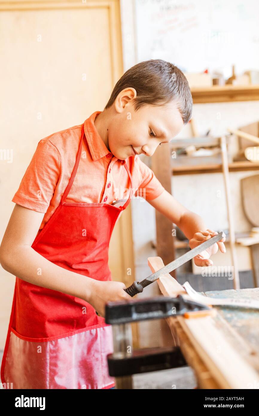 Little talented genius boy works with wood in a carpentry The