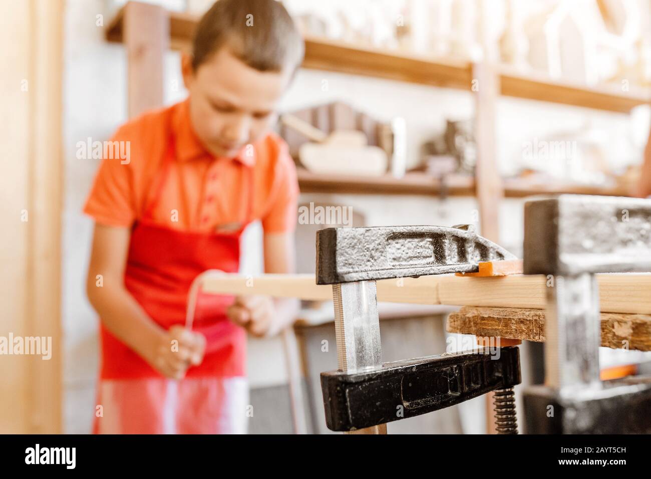 Little talented genius boy works with wood in a carpentry The
