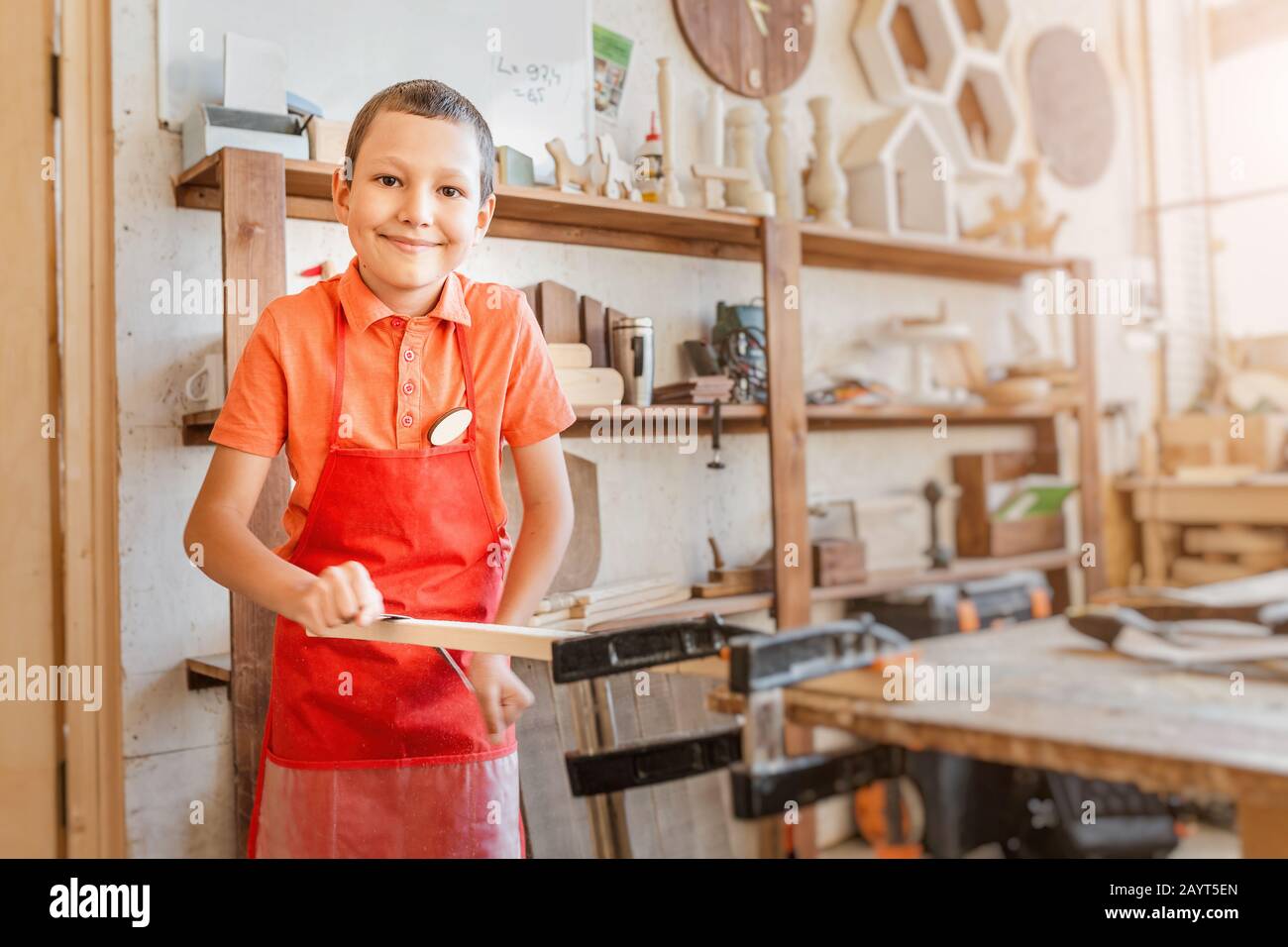 Little talented genius boy works with wood in a carpentry The