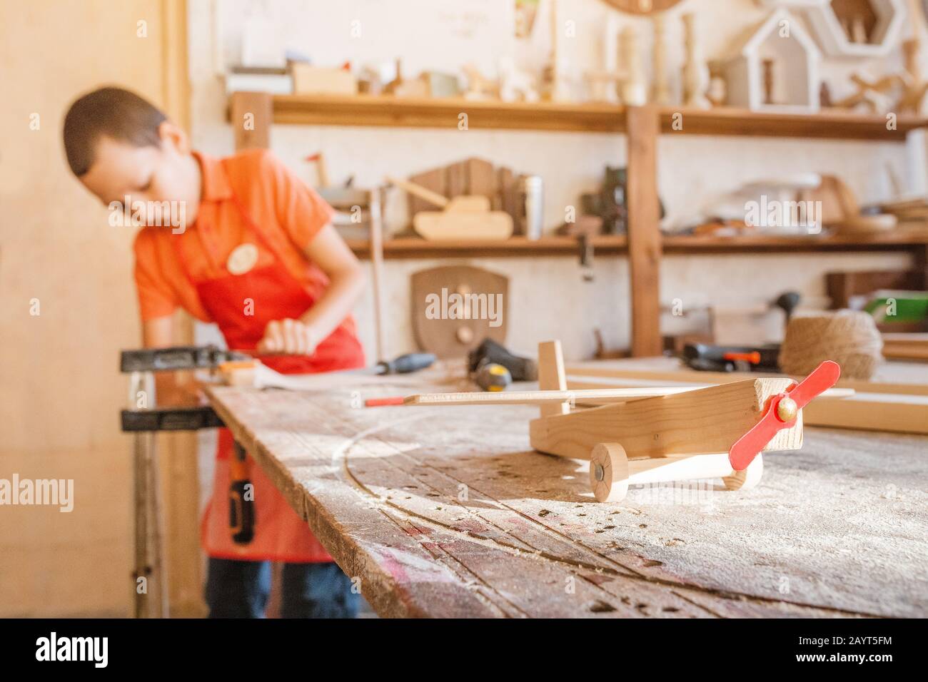 Little talented genius boy works with wood in a carpentry The