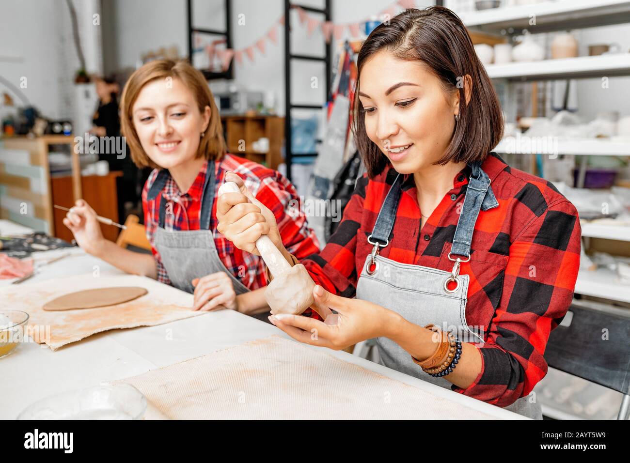 Young woman friends create clay and ceramic art dishes in pottery