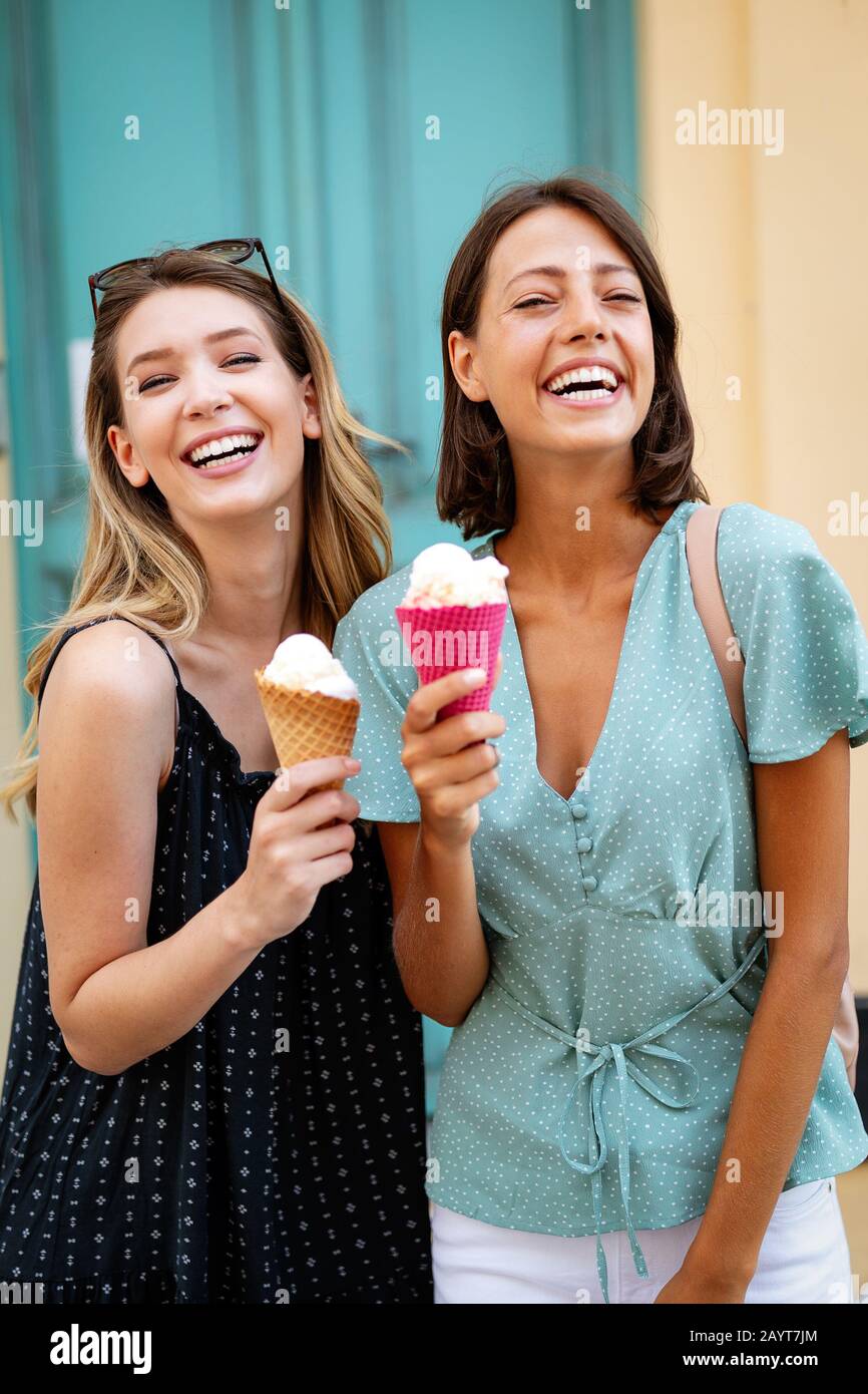 Two young women friends having fun and eating ice cream outdoor Stock Photo