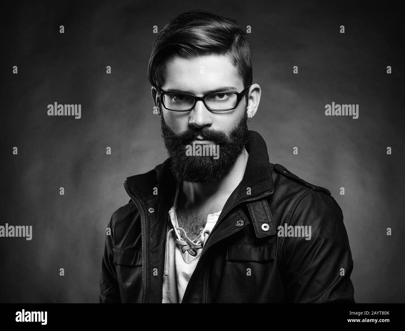 Portrait of handsome man with beard and mustache. Close-up image of serious brutal bearded man on dark background. Man with glasses. Black and white p Stock Photo