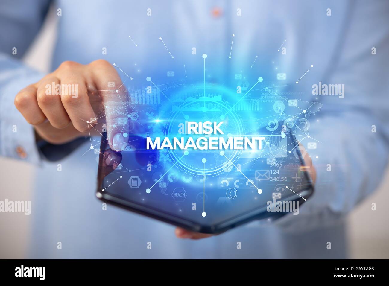 Businessman holding a foldable smartphone with RISK MANAGEMENT inscription, new business concept Stock Photo