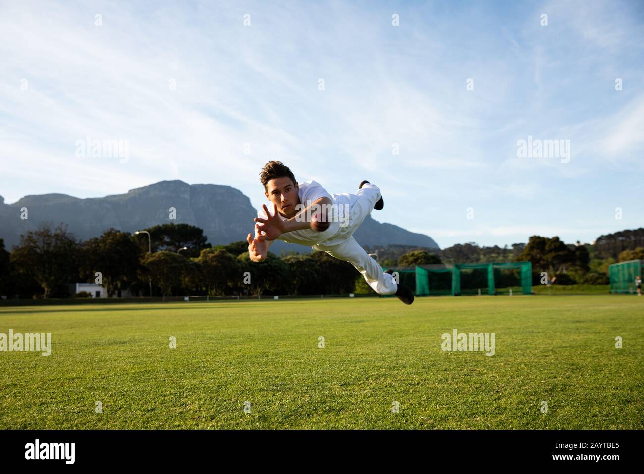 Cricket player trying to catch a cricket ball on the pitch Stock Photo