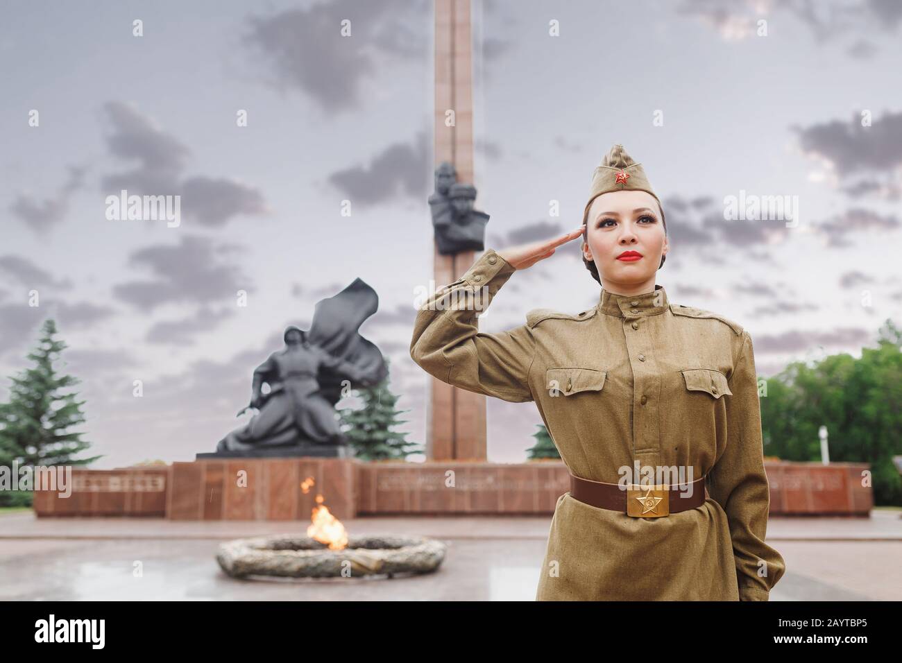 A girl in an old Soviet military uniform salute near the eternal flame. The celebration and commemoration of the Second World War on May 9 Stock Photo