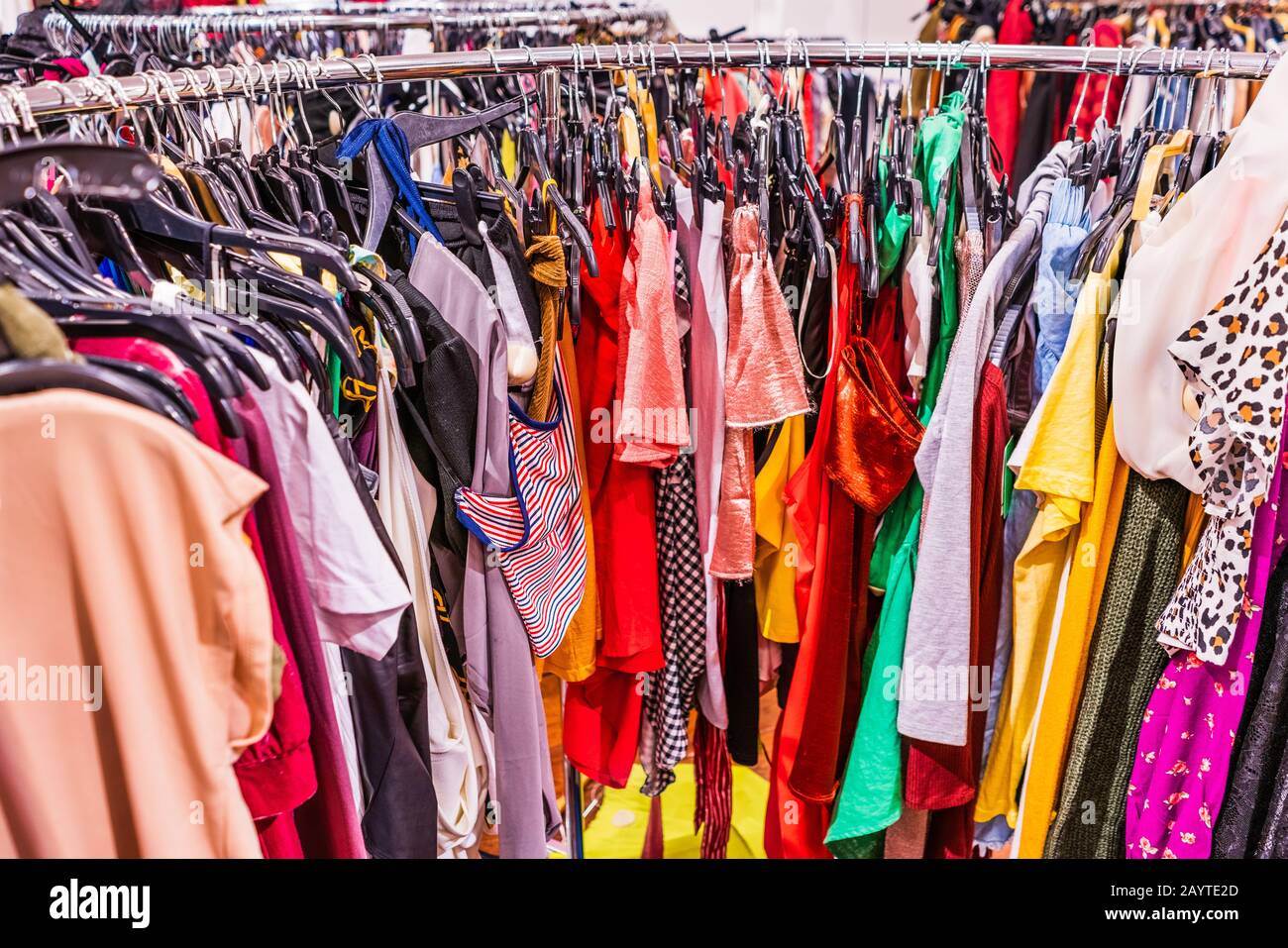 Crowded clearance section in a clothing store, with various colorful garments placed tightly on racks in no particular order; fast fashion concept Stock Photo