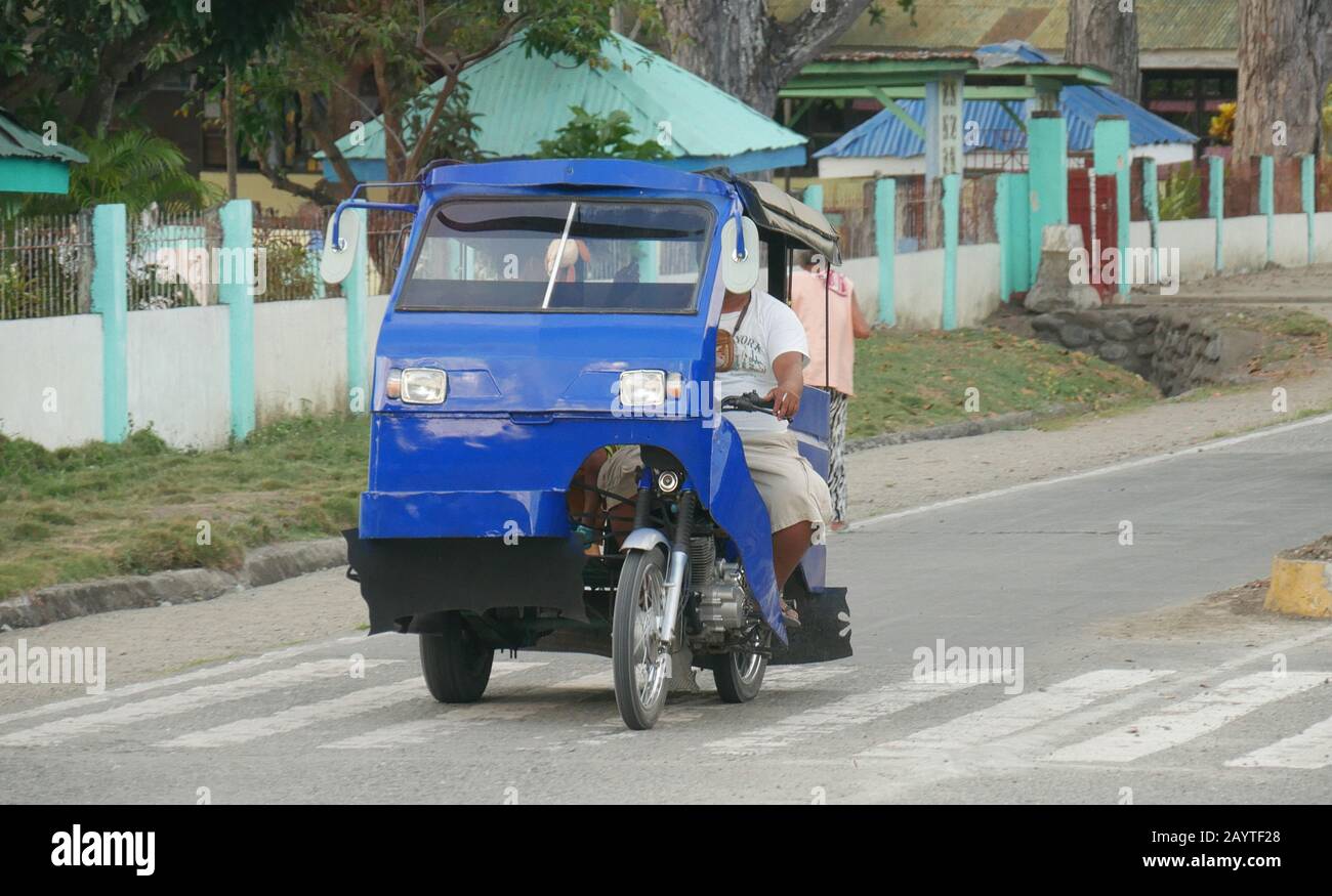 Governor Generoso, Davao Oriental, Philippines-March 2016: A tricycle plies along a side road with passengers. Stock Photo