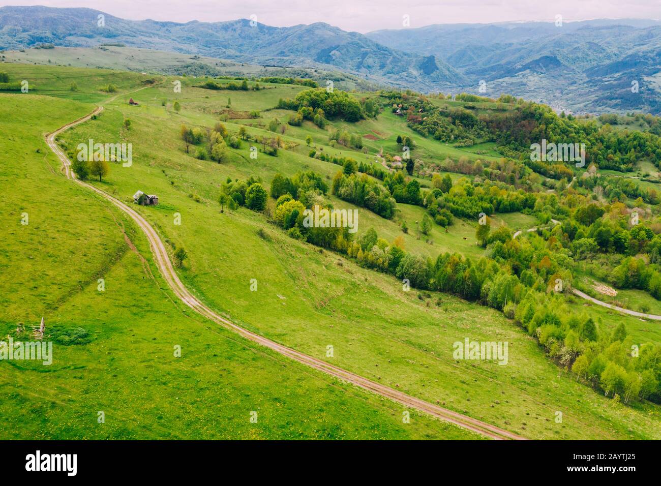 Drone view of green meadows, small houses and roads in Transylvania, Romania. Stock Photo