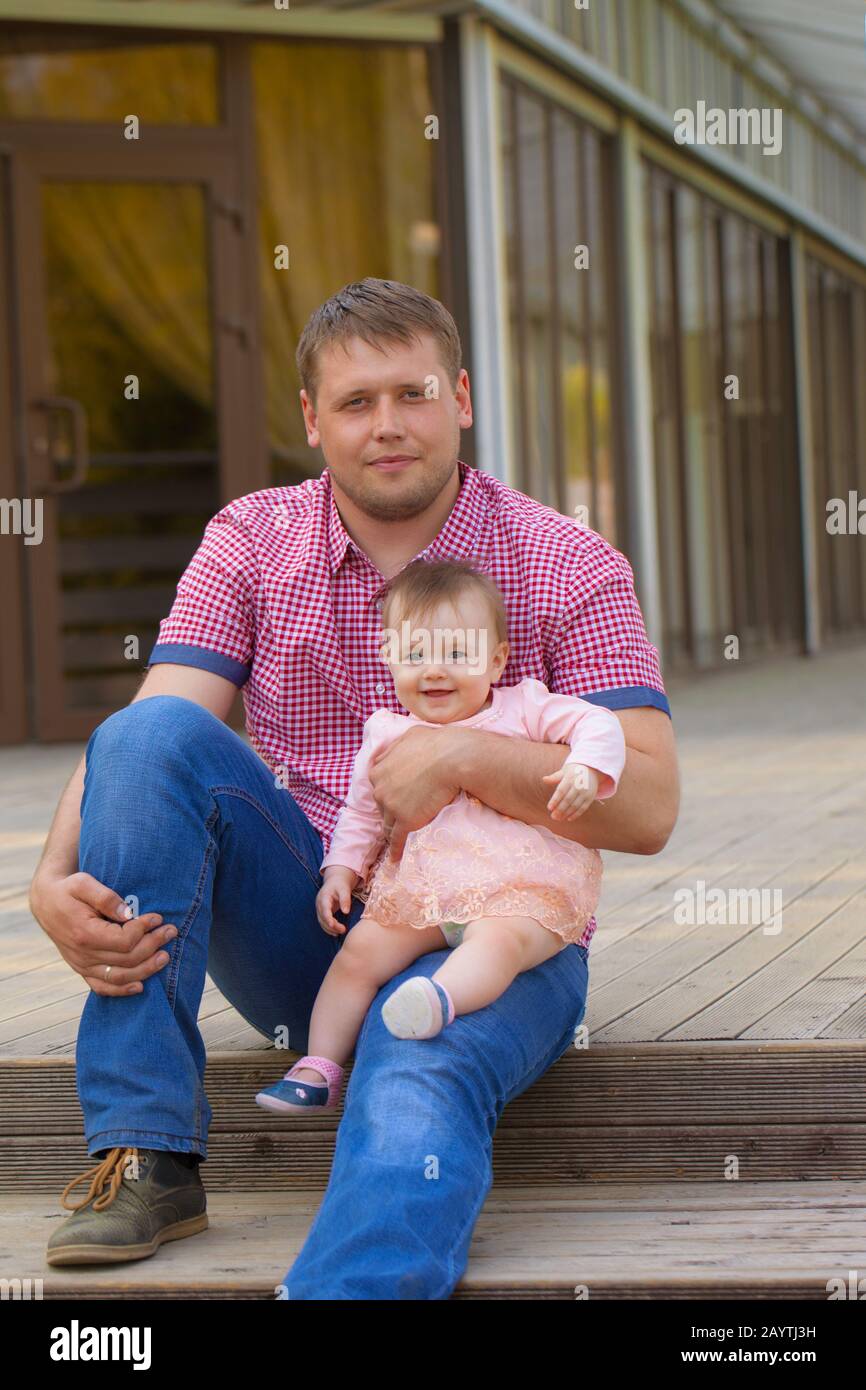 Dad and daughter. Manly guy with a cute baby in her arms. Family walk ...