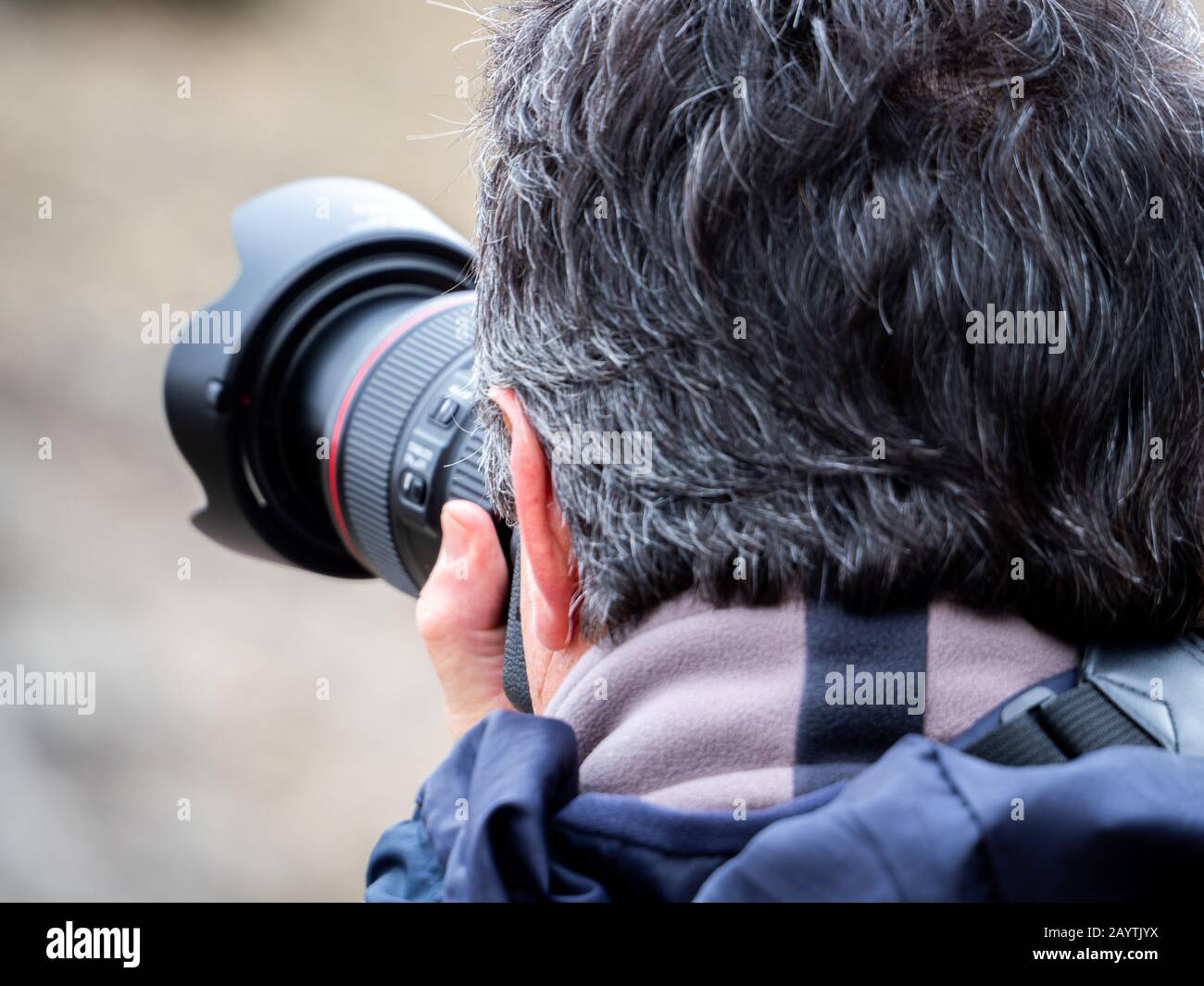 View from behind of a man taking a photograph with a reflex camera and a  objective Stock Photo - Alamy