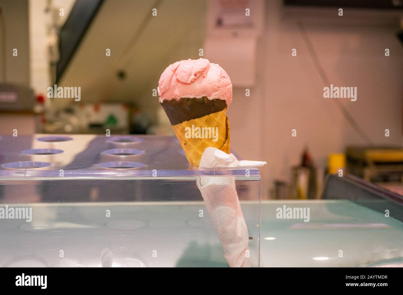 Strawberry pink ice cream in chocolate waffle cone in ice cream holder ...