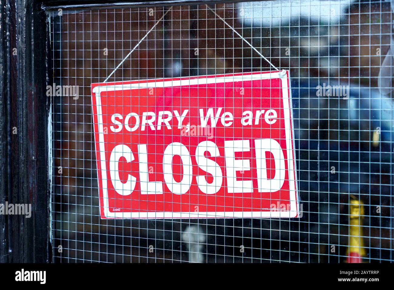 Sorry we are closed sign in shop window with wire mesh Stock Photo