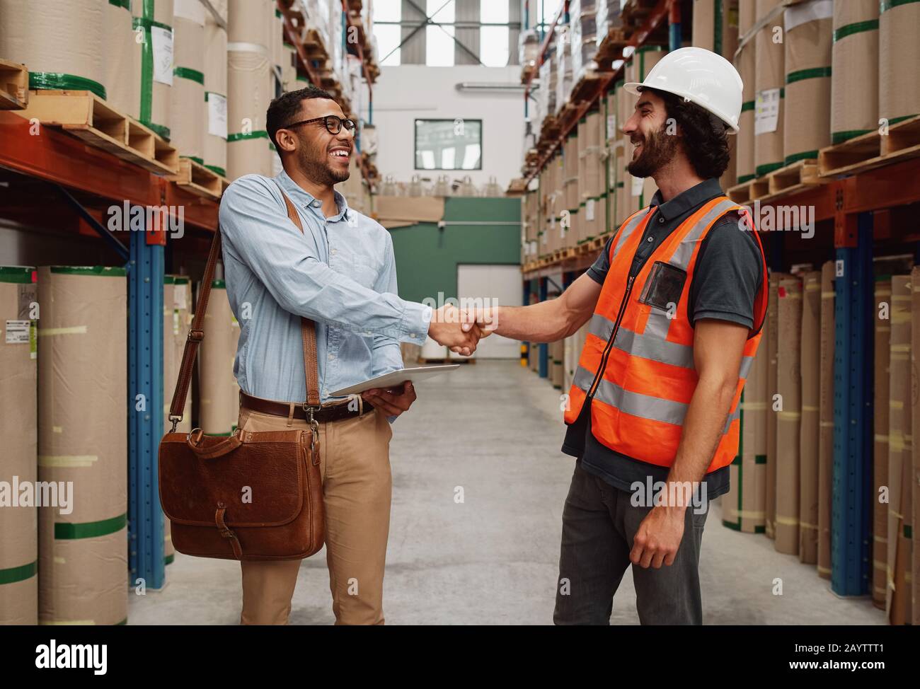 Successful partners handshaking in warehouse of large modern factory - banker and warehouse entrepreneur reach an agreement Stock Photo