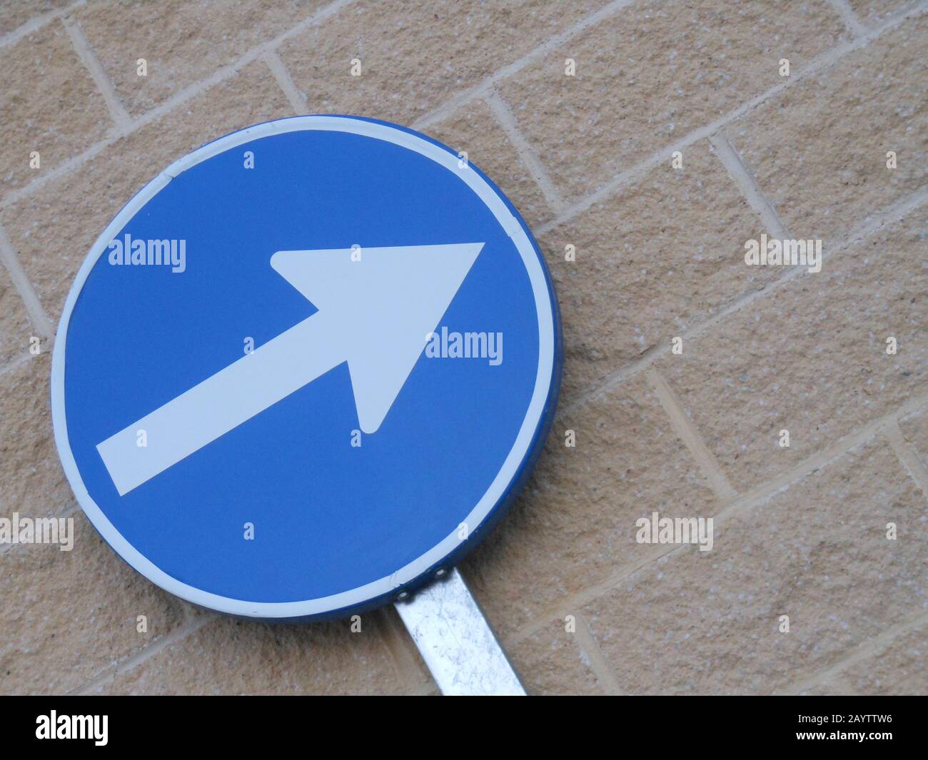 Blue traffic sign indicating the mandatory direction to follow Stock