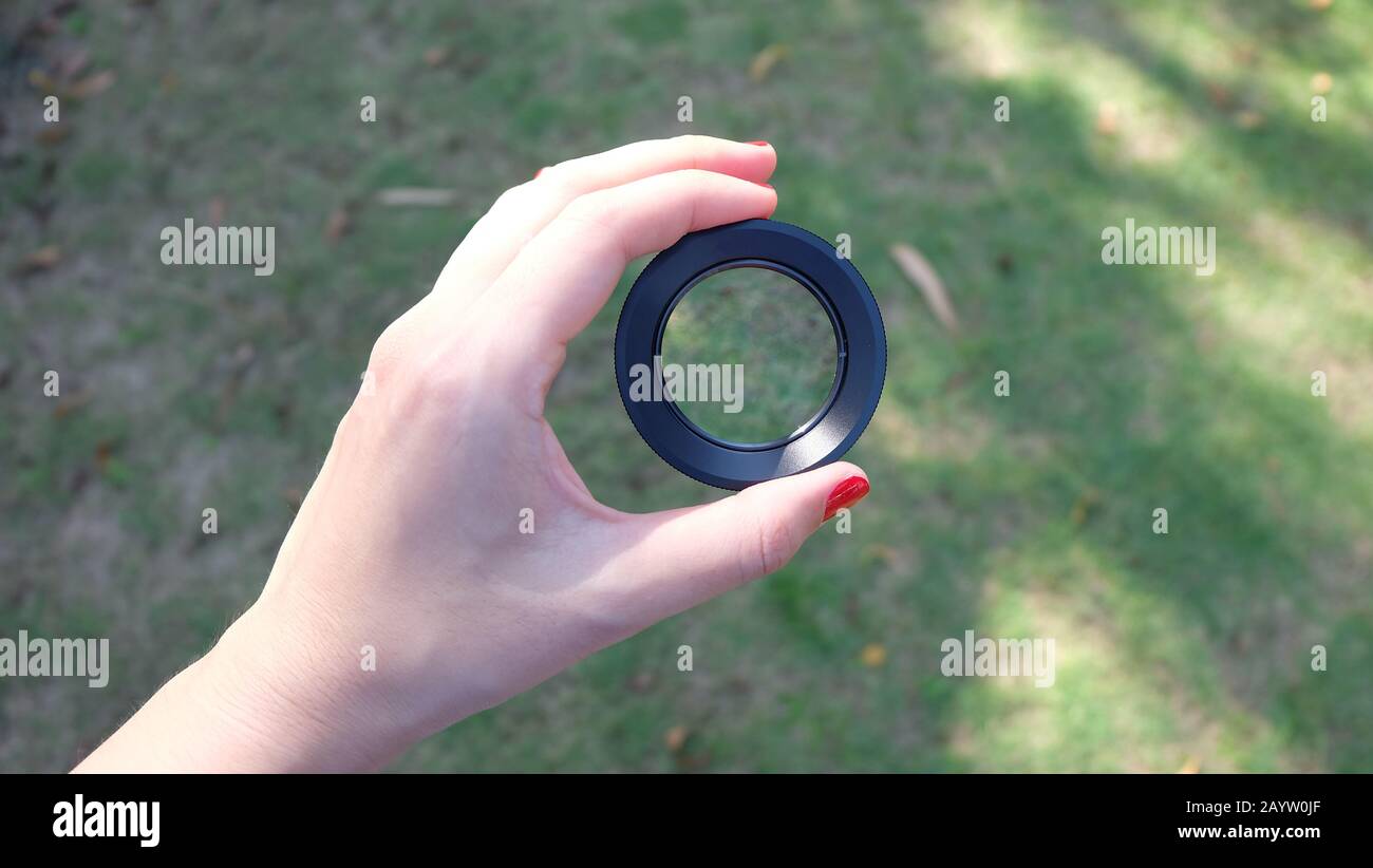 A hand holding a close-up lens, with green lawn in the background Stock ...