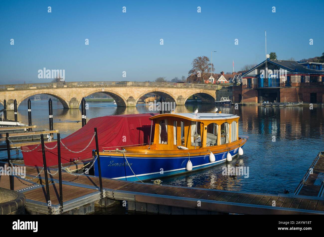 The bridge at Henley-on-Thames in low Winter sunlight with Victorian launch in the foreground and the Henley Royal Regatta Headquarters behind under a Stock Photo