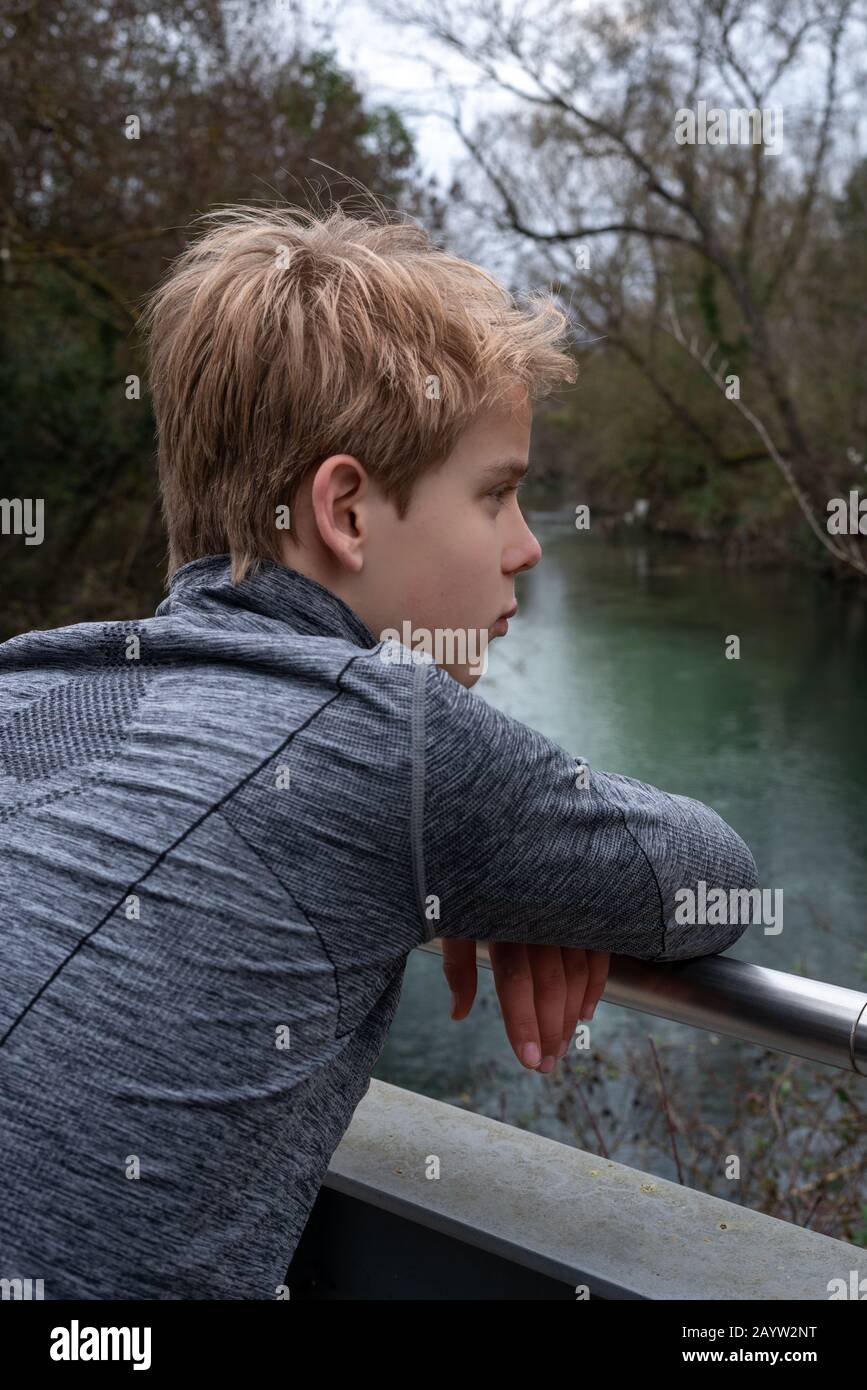 teenage boy alone  on bridge over river in the countryside ;Thinking Stock Photo