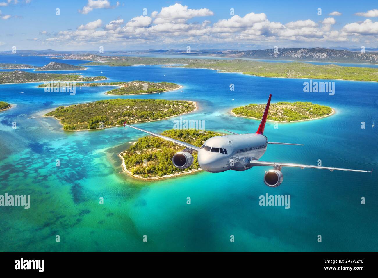 Airplane is flying over small islands and sea at sunset Stock Photo