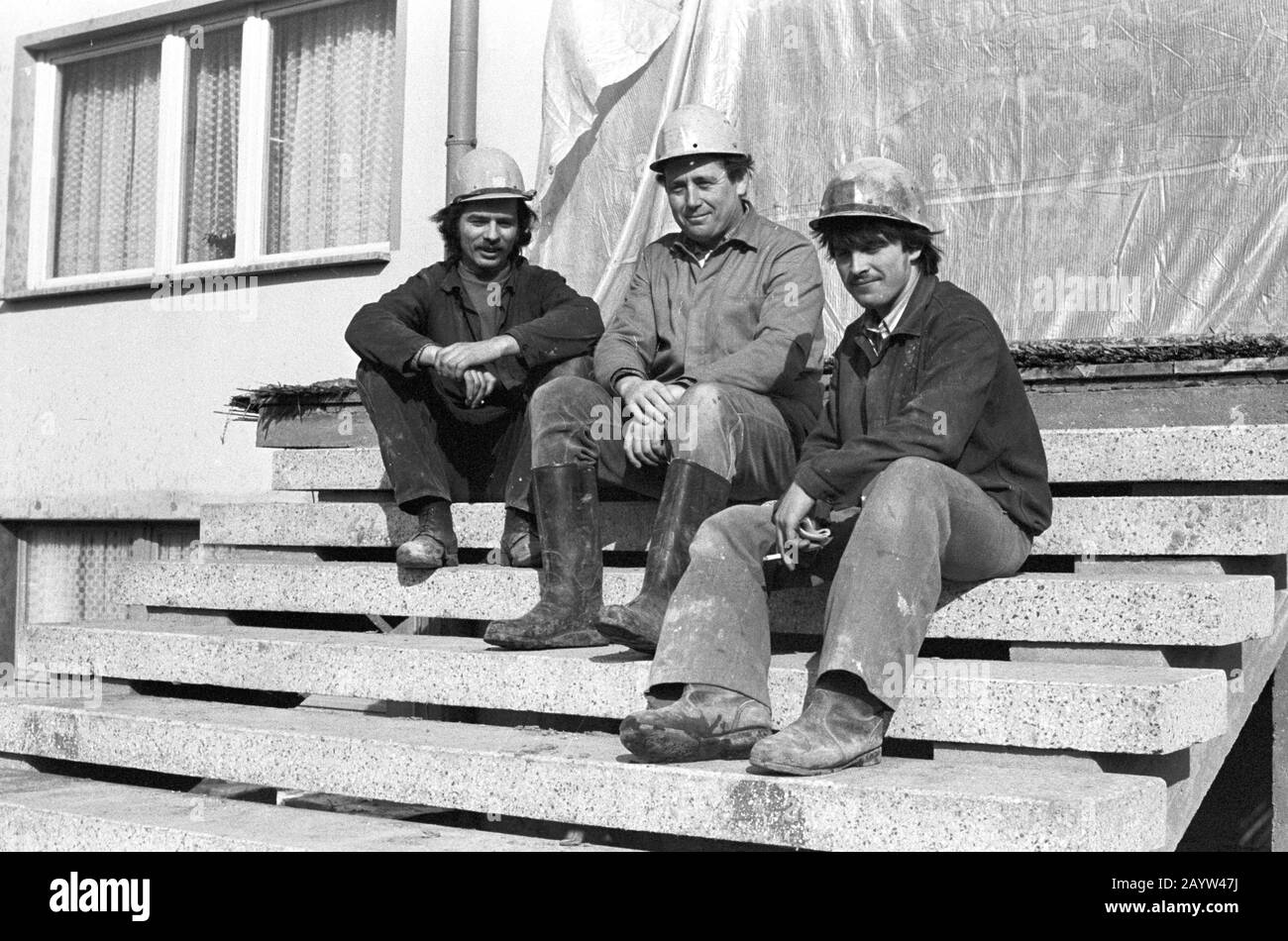 01 January 1980, Saxony, Leipzig: At the beginning of the eighties, young construction workers wearing construction helmets sit on a construction site in the Leipzig region and present themselves to the photographer as a young collective of neurons. In the companies these were promoted in connection with the fair of the masters of tomorrow. Exact date of recording not known. Photo: Volkmar Heinz/dpa-Zentralbild/ZB Stock Photo