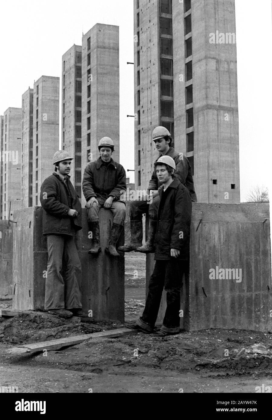 01 January 1980, Saxony, Leipzig: Young construction workers wearing construction helmets stand on a building site and present themselves to the photographer as a young collective of newcomers. In the companies these were promoted in connection with the fair of the masters of tomorrow. Exact date of recording not known. Photo: Volkmar Heinz/dpa-Zentralbild/ZB Stock Photo