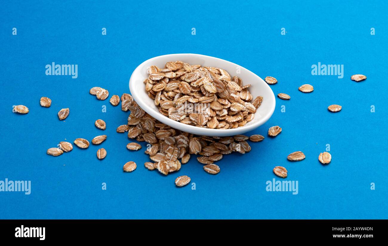 Oat rye flakes on blue color background Stock Photo