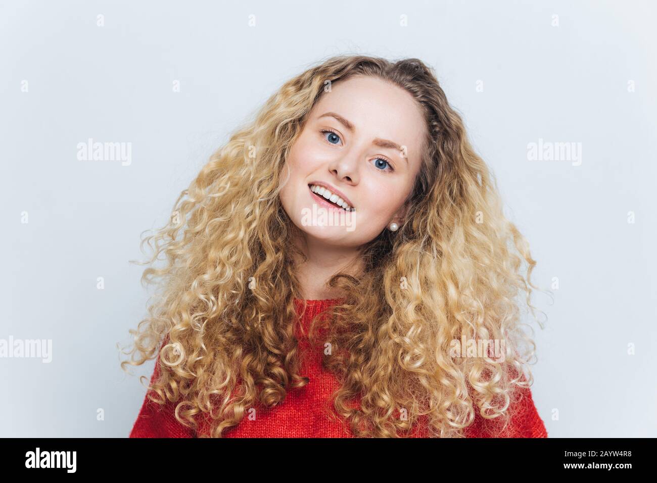 Glad lovely adorable young beautiful woman wth curly hair, dressed casually, expresses positive emotions and feelings being satisfied to have date wit Stock Photo