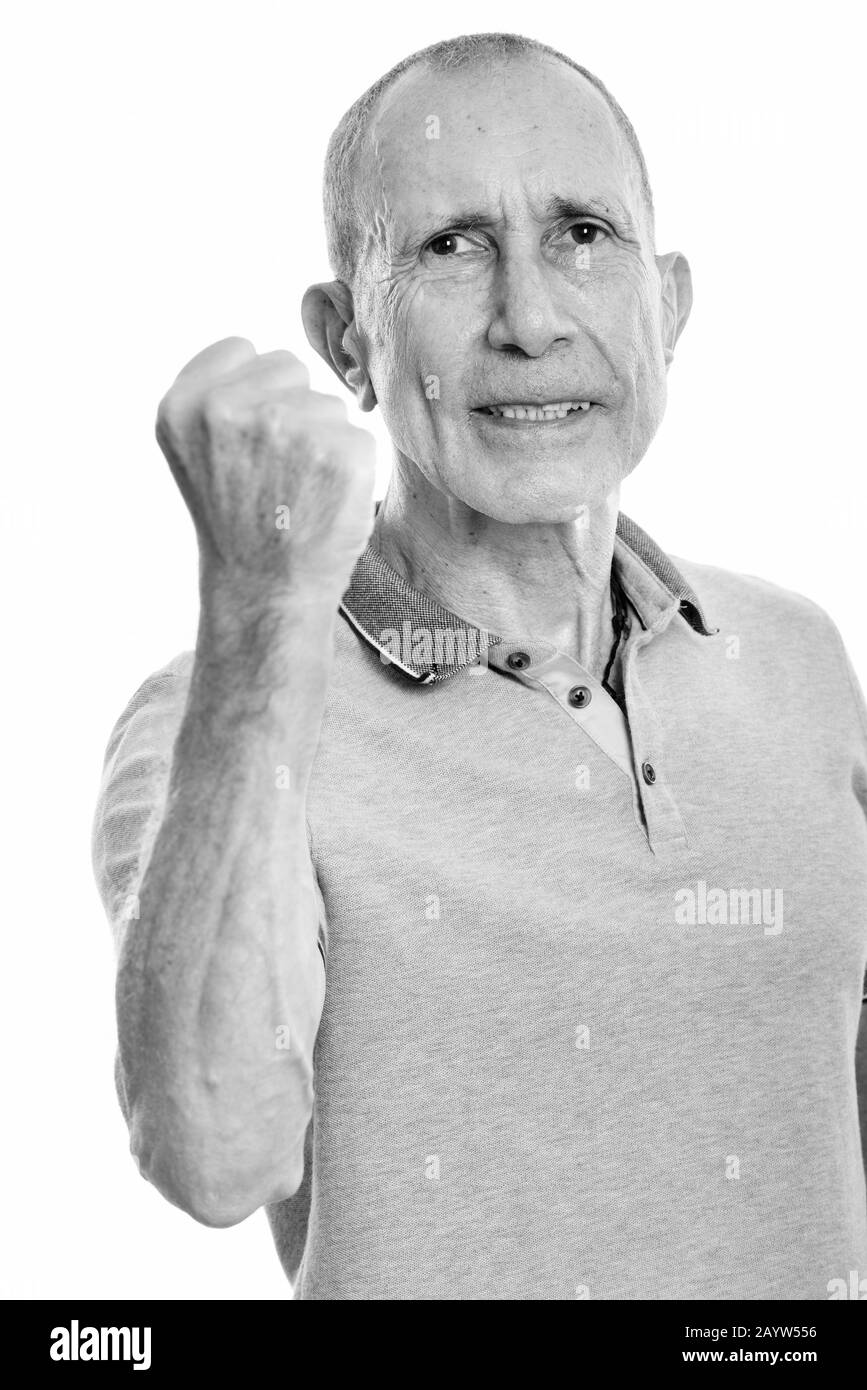 Studio shot of angry senior man with arm raised Stock Photo