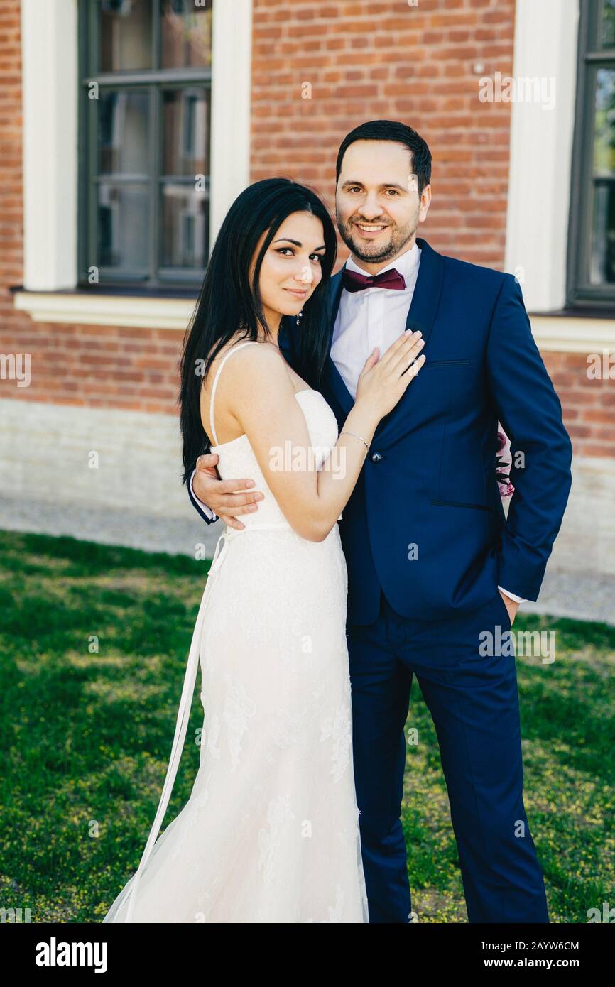 Romantic couple in love celebrate their wedding, embrace each other affectionately, have happy expressions, stand outdoor. Nice young wedding couple a Stock Photo