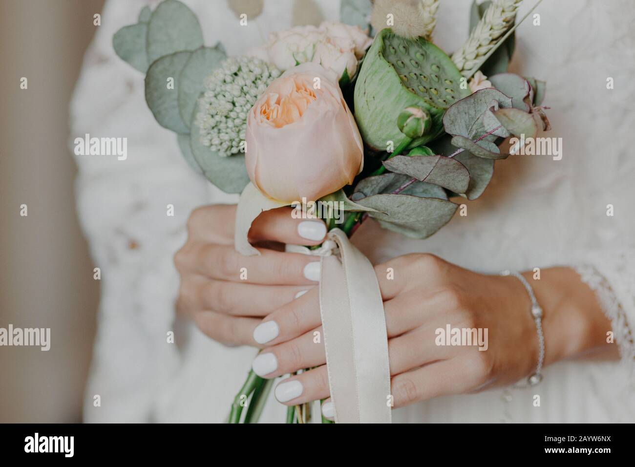 Beautiful bride with nice bouquet prepares for wedding ceremony. Brides hands hold flowers indoor. Photo for commercial. Celebration concept Stock Photo