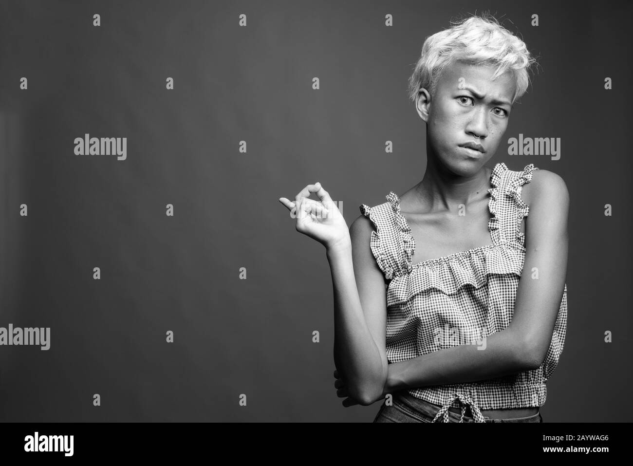 Young beautiful rebellious woman with short hair against gray background Stock Photo