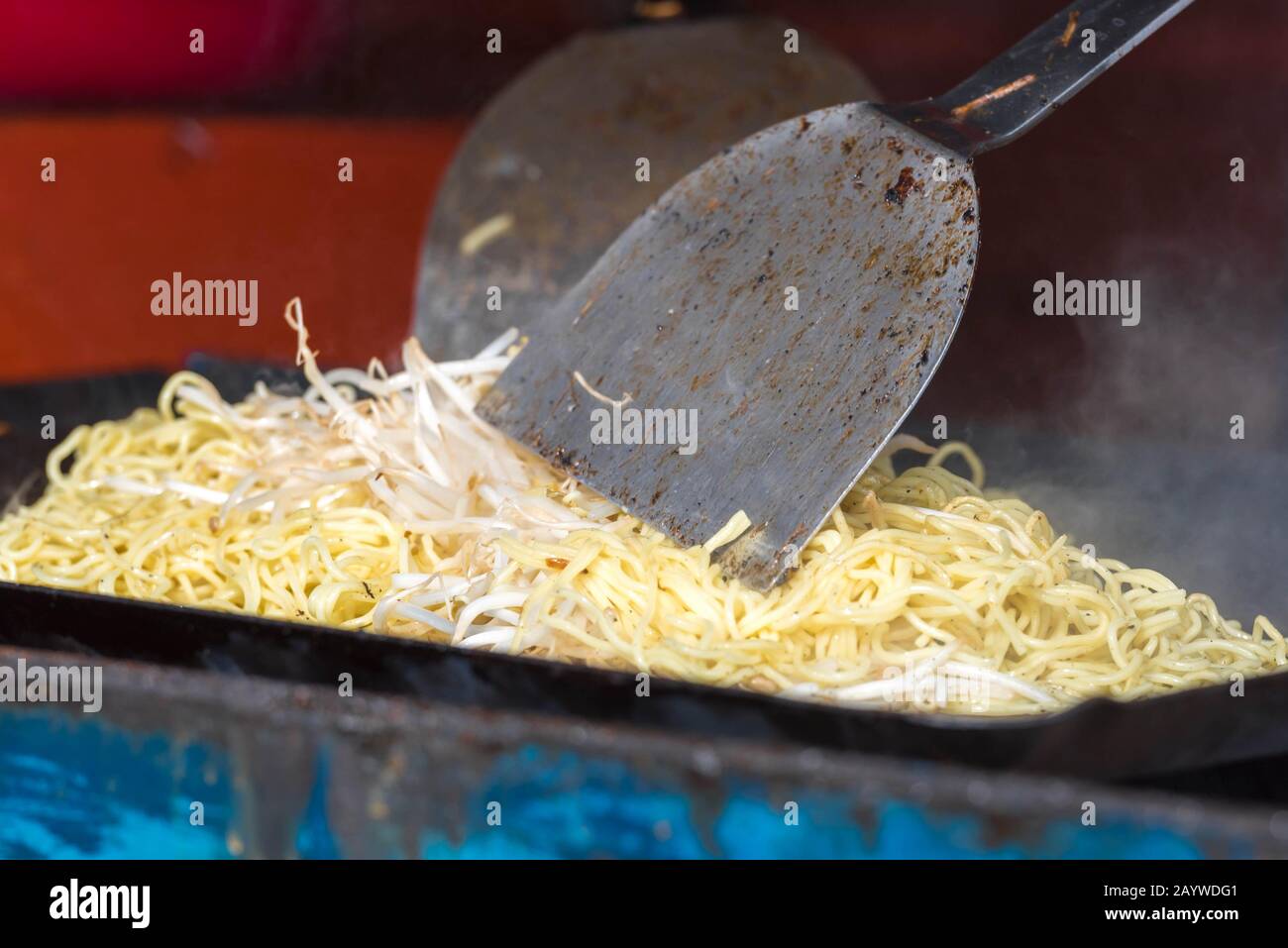 Smoking and steaming yakisoba being cooked traditionally on a yakisoba flat pan at a stall. It is a popular Japanese noodles. Stock Photo