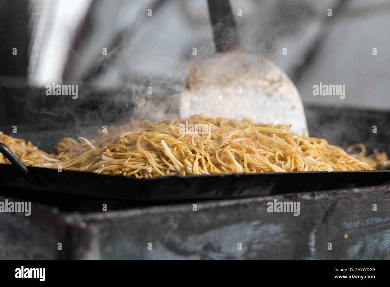 Smoking and steaming yakisoba being cooked traditionally on a yakisoba flat pan at a stall. It is a popular Japanese noodles. Stock Photo