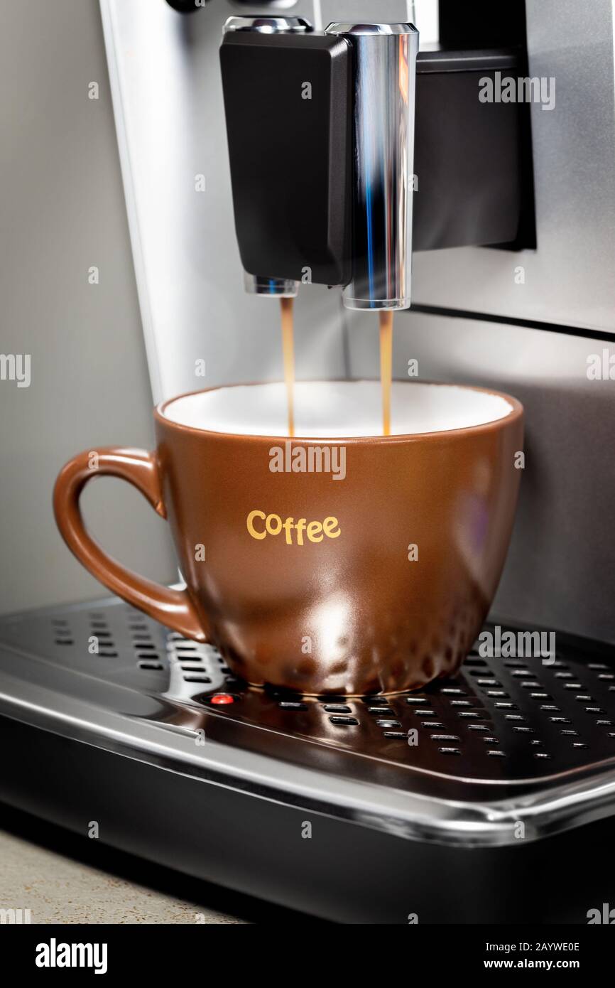 A cup of coffee is poured in a coffee machine. Closeup fragment Stock Photo