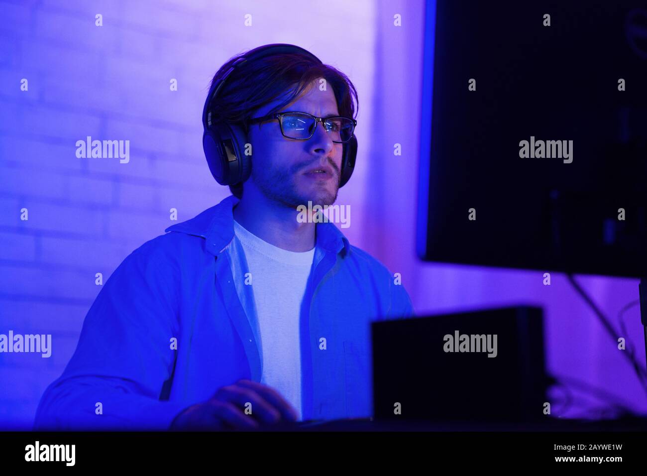 Concentrated Hacker Working On PC Computer Sitting Indoor, Low Light Stock Photo