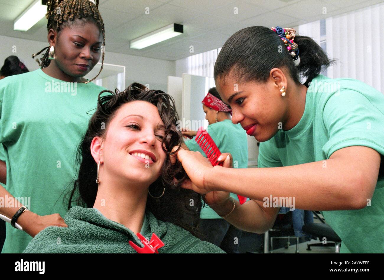 trainee hairdressers practice styling hair with each other Stock Photo