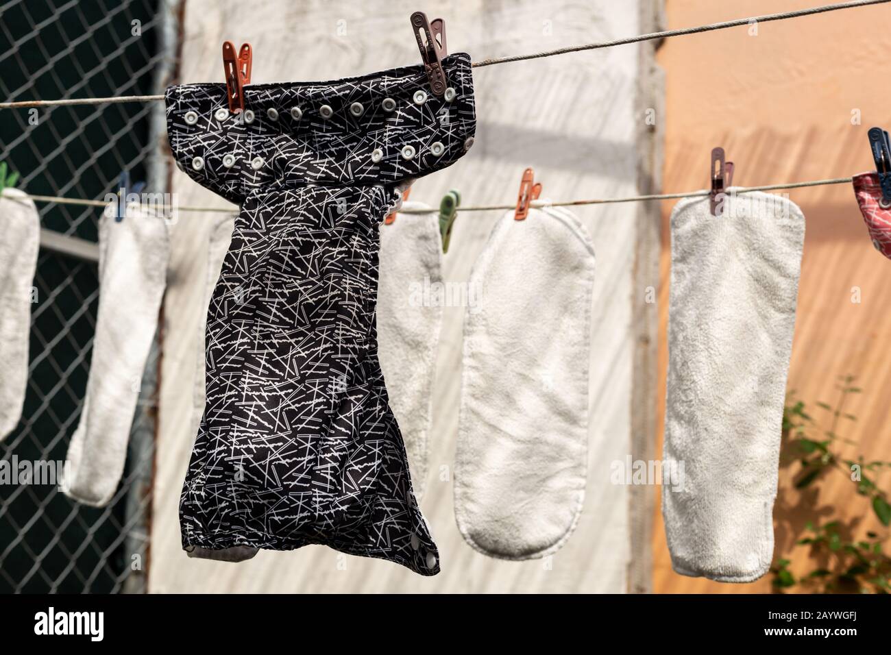 Washed cloth diapers hanging outside on a clothesline to dry in the sun