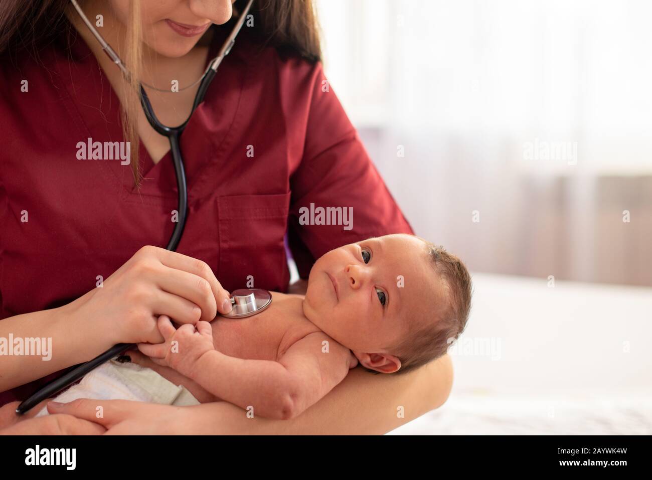 Pediatric young doctor exams newborn baby girl with stethoscope in hospital Stock Photo